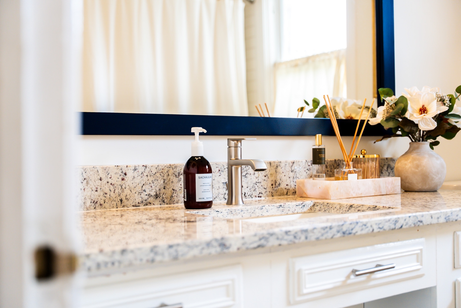 Granite countertop with navy-framed mirror and apothecary bottles at Casa Thorman